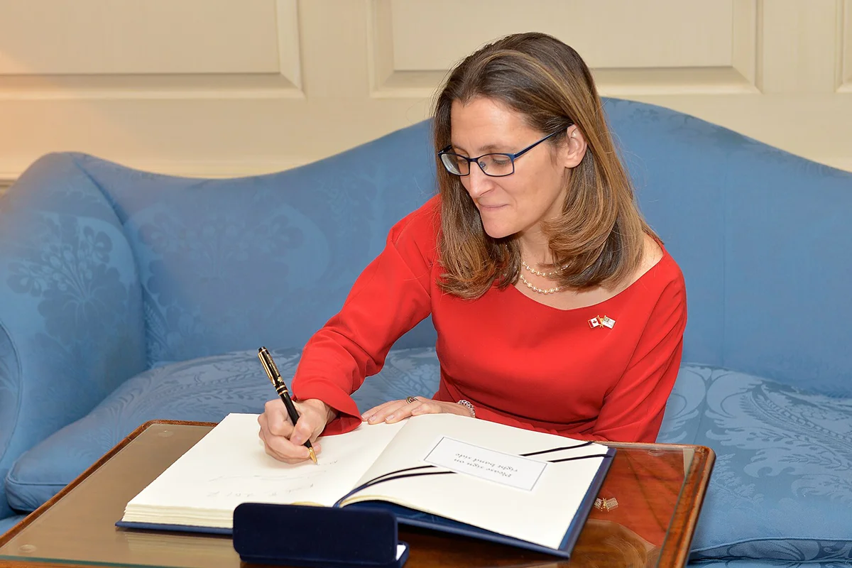 Woman in red dress on blue sofa signing a large book